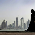 
              FILE- A Qatari woman walks in front of the city skyline in Doha, Qatar on May 14, 2010. After FIFA awarded the World Cup to Qatar, there were questions about what women would be allowed to wear. The local organizing guide says women must dress modestly with sleeves, long pants or long skirts.  (AP Photo/Kamran Jebreili, File)
            