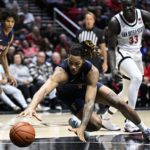 
              Cal State Fullerton forward Lathaniel Bastian, center, dives for the ball as San Diego State forward Nathan Mensah (31), right, looks on during the first half of an NCAA college basketball game Monday, Nov. 7, 2022, in San Diego. (AP Photo/Denis Poroy)
            
