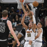 
              Denver Nuggets' Aaron Gordon (50) and Michael Porter Jr., right, tangle with San Antonio Spurs' Jeremy Sochan (10) under the net during the first half of an NBA basketball game, Monday, Nov. 7, 2022, in San Antonio. (AP Photo/Darren Abate)
            