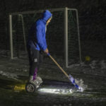
              A man rides his hoverboard as he clears snow from a pitch ahead of a soccer game in Irpin, Kyiv region, Ukraine, Tuesday, Nov. 29, 2022. For soccer lovers in Ukraine, Russia's invasion and the devastation it has wrought have created uncertainties about both playing the sport and watching it. For Ukrainians these days, soccer trails well behind mere survival in the order of priorities. (AP Photo/Andrew Kravchenko)
            