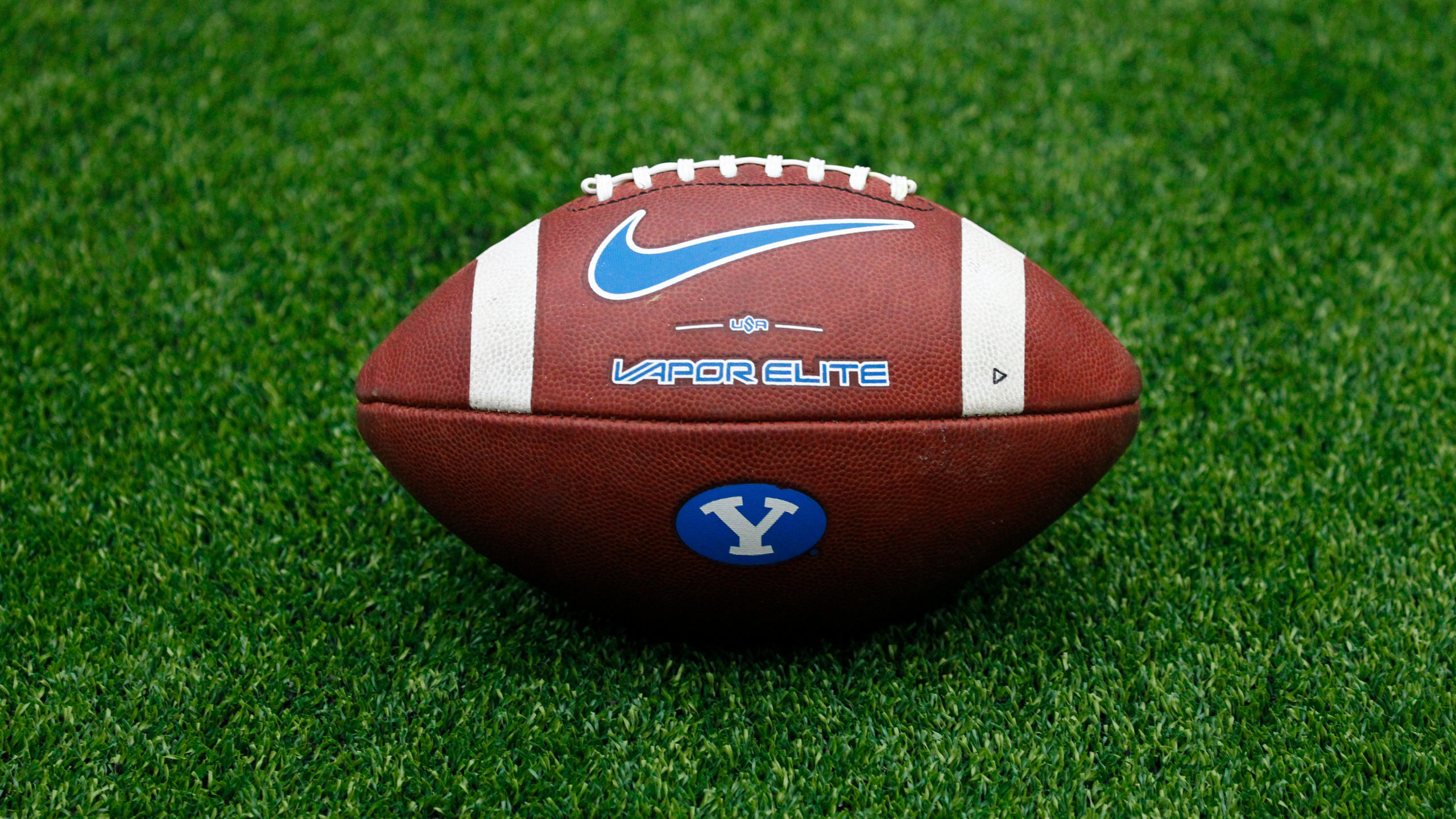 A detail view of a Nike Vapor Elite college football with a BYU logo on the artificial turf prior t...