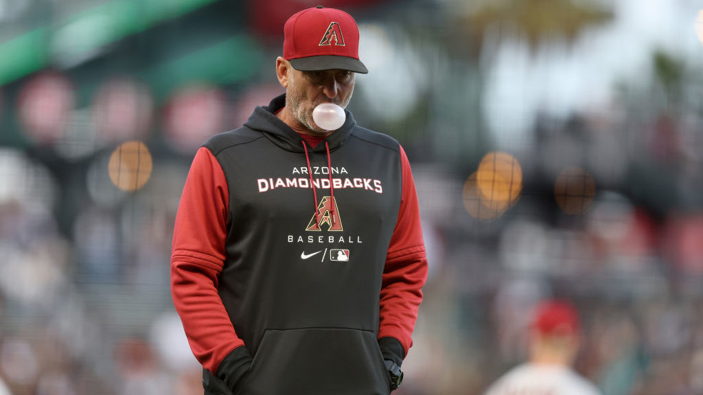 Manager Torey Lovullo #17 of the Arizona Diamondbacks blows a bubble as he walks back to the dugout...