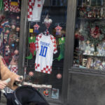 People pass by a souvenir shop with the shirt of Luka Modric, Croatia's captain, on display ahead of the team's Qatar World Cup soccer semifinal match against Argentina, in Zagreb, Croatia, Tuesday, Dec. 13, 2022. (AP Photo/Marko Drobnjakovic)