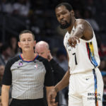 Referee Nick Buchert, left, listens to Brooklyn Nets forward Kevin Durant (7), during the first half of an NBA basketball game against the Charlotte Hornets, Saturday, Dec. 31, 2022, in Charlotte, N.C. (AP Photo/Matt Kelley)