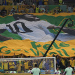 
              Soccer fans hold a giant Brazilian flag with a picture of Brazilian soccer legend Pele with a message reading in English "Pele, Get well soon," during the World Cup group G soccer match between Cameroon and Brazil, at the Lusail Stadium in Lusail, Qatar, Friday, Dec. 2, 2022. (AP Photo/Pavel Golovkin)
            