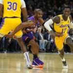 Los Angeles Lakers guard Dennis Schroder (17) drives past Phoenix Suns guard Chris Paul, center, with Lakers center Damian Jones (30) setting a pick during the first half of an NBA basketball game, Monday, Dec. 19, 2022, in Phoenix. (AP Photo/Rick Scuteri)