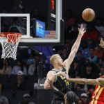 Charlotte Hornets center Mason Plumlee, top left, attempts to block a shot by Atlanta Hawks forward De'Andre Hunter, right, during the first half of an NBA basketball game Friday, Dec. 16, 2022, in Charlotte, N.C. (AP Photo/Rusty Jones)