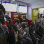 
              Customers watch screens in a sports betting shop in the low-income Kibera neighborhood of the capital Nairobi, Kenya, Monday, Dec. 5, 2022. Although sports betting is a global phenomenon and a legitimate business in many countries, the stakes are high on the continent of 1.3 billion people because of lax or non-existent regulation, poverty and widespread unemployment. (AP Photo/Brian Inganga)
            