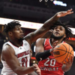 Western Kentucky guard Dayvion McKnight (20) attempts a shot as Louisville forward Sydney Curry (21) defends during the first half of an NCAA college basketball game in Louisville, Ky., Wednesday, Dec. 14, 2022. (AP Photo/Timothy D. Easley)