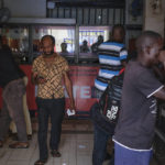 
              Moses Ssali, center, looks at his phone after placing bets at the Fortebet sports betting shop in the Ntinda area of the capital Kampala, Uganda, Tuesday, Dec. 6, 2022. In Uganda, an East African country where annual income per capita was $840 in 2020, many see sports betting as a path to survival and perhaps even prosperity. (AP Photo/Hajarah Nalwadda)
            