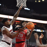 Western Kentucky guard Dayvion McKnight (20) attempts a shot over Louisville forward Sydney Curry (21), left, and forward Kamari Lands (22) during the first half of an NCAA college basketball game in Louisville, Ky., Wednesday, Dec. 14, 2022. (AP Photo/Timothy D. Easley)