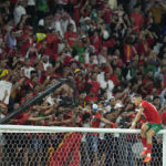 Morocco's Jawad El Yamiq climbs on the crossbar as he celebrates his team's victory during the World Cup round of 16 soccer match between Morocco and Spain, at the Education City Stadium in Al Rayyan, Qatar, Tuesday, Dec. 6, 2022. (AP Photo/Ebrahim Noroozi)