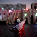 
              A woman with a mask holds a flag from Qatar at Katara Cultural Village in Doha, Qatar, Sunday, Dec. 11, 2022. (AP Photo/Natacha Pisarenko)
            
