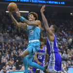Charlotte Hornets guard Kelly Oubre Jr. (12) lays the ball up past Sacramento Kings forward Harrison Barnes during the first quarter of an NBA basketball game in Sacramento, Calif., Monday, Dec. 19, 2022. (AP Photo/Randall Benton)
