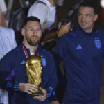 
              Argentina's Lionel Messi holds the FIFA World Cup trophy as he deplanes, with coach Lionel Scaloni, in Buenos Aires, Argentina, Tuesday, Dec. 20, 2022. (AP Photo/Gustavo Garello)
            