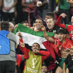 Morocco's team makes a group photo on the pitch, holding the Palestinian flag, after winning the World Cup round of 16 soccer match between Morocco and Spain, at the Education City Stadium in Al Rayyan, Qatar, Tuesday, Dec. 6, 2022. (AP Photo/Martin Meissner)