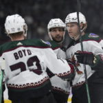 Arizona Coyotes' Jakob Chychrun (6), Shayne Gostisbehere (14) and Travis Boyd (72) celebrate Chychrun's goal against the Vancouver Canucks during the second period of an NHL hockey game Saturday, Dec. 3, 2022, in Vancouver, British Columbia. (Darryl Dyck/The Canadian Press via AP)
