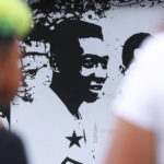 
              Fans of soccer star Pele walk past mural with an image of the player outside the Vila Belmiro stadium in Santos, Brazil, Thursday, Dec. 29, 2022. Pele, the Brazilian king of soccer who won a record three World Cups and became one of the most commanding sports figures of the last century, died in Sao Paulo. He was 82. (AP Photo/Fabricio Costa)
            