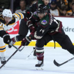 Arizona Coyotes defenseman Shayne Gostisbehere (14) tries to keep the puck away from Boston Bruins left wing Taylor Hall (71) during the first period of an NHL hockey game in Tempe, Ariz., Friday, Dec. 9, 2022. (AP Photo/Ross D. Franklin)