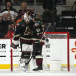 Arizona Coyotes defenseman Troy Stecher (51) congratulates goaltender Connor Ingram, left, as time expires in the team's NHL hockey game against the Colorado Avalanche in Tempe, Ariz., Tuesday, Dec. 27, 2022. The Coyotes won 6-3. (AP Photo/Ross D. Franklin)