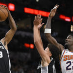 San Antonio Spurs' Alize Johnson (19) and Isaiah Roby, center, grab for the rebound against Phoenix Suns' Deandre Ayton (22) during the first half of an NBA basketball game, Sunday, Dec. 4, 2022, in San Antonio. (AP Photo/Darren Abate)