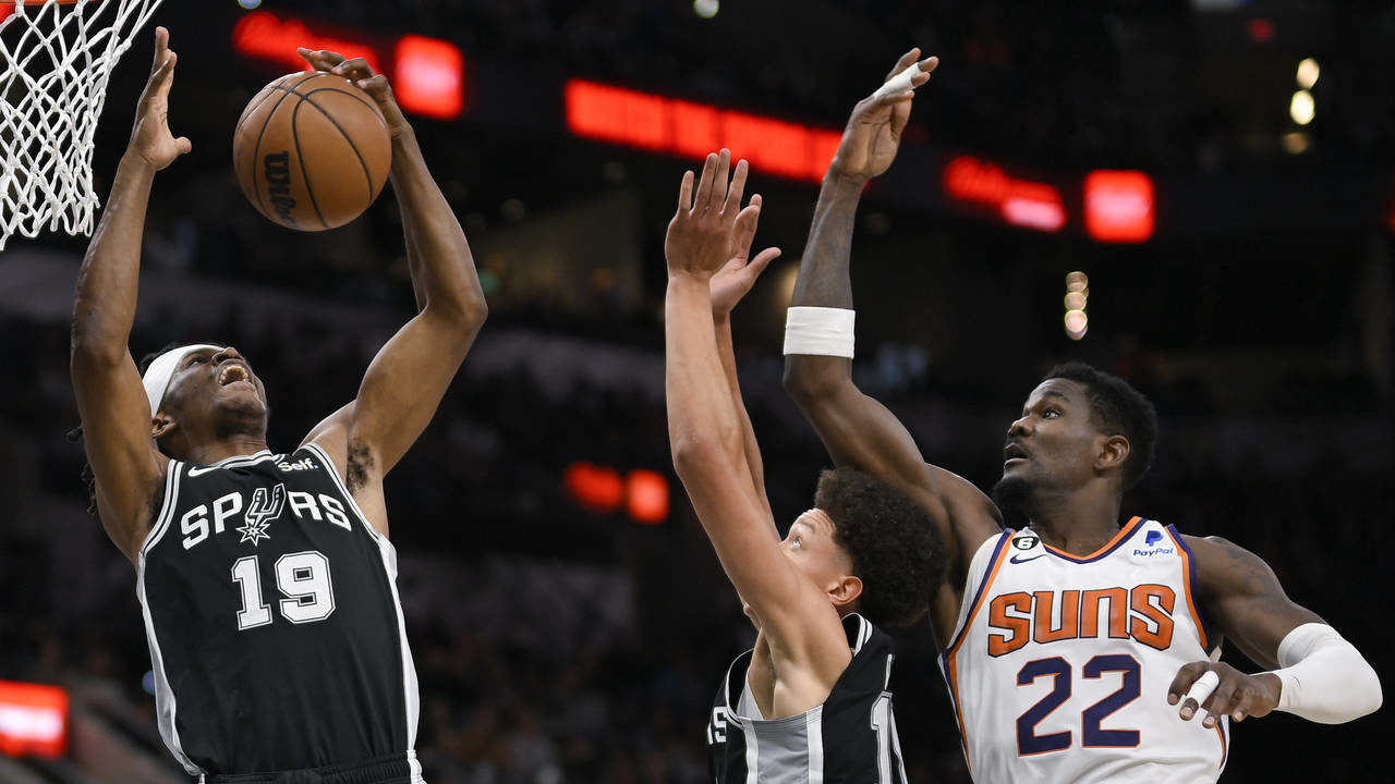 San Antonio Spurs' Alize Johnson (19) and Isaiah Roby, center, grab for the rebound against Phoenix...