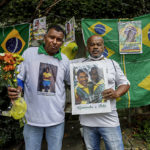 
              Antonio da Paz, left, and Renato Souza stand in front of the Albert Einstein Hospital holding memorabilia honoring Brazilian soccer star Pele, in Sao Paulo, Brazil, Friday, Dec. 30, 2022. Edson Arantes do Nascimento, known to the world as Pele, died at the hospital Thursday at the age of 82. (AP Photo/Marcelo Chello)
            