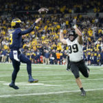Michigan quarterback J.J. McCarthy (9) throws for a 2-point conversion over Purdue defensive end Jack Sullivan (99) during the second half of the Big Ten championship NCAA college football game, Saturday, Dec. 3, 2022, in Indianapolis. (AP Photo/Michael Conroy)