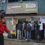 
              Customers queue outside a sports betting shop in the low-income Kibera neighborhood of the capital Nairobi, Kenya, Monday, Dec. 5, 2022. Although sports betting is a global phenomenon and a legitimate business in many countries, the stakes are high on the continent of 1.3 billion people because of lax or non-existent regulation, poverty and widespread unemployment. (AP Photo/Brian Inganga)
            