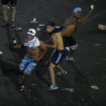 
              Soccer fans who waited for hours for a homecoming parade for the players who won the World Cup, threaten with glass bottles police who were working to remove the fans, in Buenos Aires, Argentina, Tuesday, Dec. 20, 2022. A parade to celebrate the champions was abruptly cut short Tuesday as millions of people poured onto thoroughfares, highways and overpasses in a chaotic attempt to catch a glimpse of the national team. (AP Photo/Gustavo Garello)
            