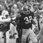 
              FILE - Pittsburgh Steelers' Franco Harris (32) eludes a tackle by Oakland Raiders' Jimmy Warren as he runs 42-yards for a touchdown after catching a deflected pass during an AFC Divisional NFL football playoff game in Pittsburgh, Dec. 23, 1972. Harris' scoop of a deflected pass and subsequent run for the winning touchdown — forever known as the "Immaculate Reception" — has been voted the greatest play in NFL history. On the 50th anniversary of the "Immaculate Reception" — Friday, Dec. 23, 2022 — Pittsburghers recall how it boosted morale during the collapse of the steel industry and has served as a cultural rallying point ever since. (AP Photo/Harry Cabluck, File)
            