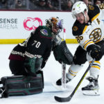Arizona Coyotes goaltender Karel Vejmelka (70) slides over to make the save on a shot by Boston Bruins right wing David Pastrnak (88) during the second period of an NHL hockey game in Tempe, Ariz., Friday, Dec. 9, 2022. (AP Photo/Ross D. Franklin)