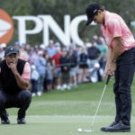 
              Tiger Woods, left, watches his son Charlie Woods, right, putt on the 18th green during the first round of the PNC Championship golf tournament Saturday, Dec. 17, 2022, in Orlando, Fla. (AP Photo/Kevin Kolczynski)
            