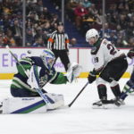 Vancouver Canucks goalie Spencer Martin, left, allows a goal to Arizona Coyotes' Jakob Chychrun, not seen, as Coyotes' Barrett Hayton (29) and Canucks' Luke Schenn (2) watch during the second period of an NHL hockey game Saturday, Dec. 3, 2022, in Vancouver, British Columbia. (Darryl Dyck/The Canadian Press via AP)