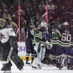 Arizona Coyotes goalie Karel Vejmelka skates off the ice as the Vancouver Canucks celebrate their overtime win in an NHL hockey game Saturday, Dec. 3, 2022, in Vancouver, British Columbia. (Darryl Dyck/The Canadian Press via AP)