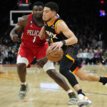 Phoenix Suns guard Devin Booker, right drives as New Orleans Pelicans forward Zion Williamson defends during the second half of an NBA basketball game, Saturday, Dec. 17, 2022, in Phoenix. (AP Photo/Matt York)