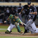 
              FILE - Oakland Athletics catcher Sean Murphy, left, tries to tag Chicago White Sox's Adam Engel (15), who scored the tying run during the ninth inning of a baseball game in Oakland, Calif., Sept. 9, 2022. The Atlanta Braves acquired catcher Murphy from the Oakland Athletics as part of a three-team deal on Monday, Dec. 12, 2022, that also sent catcher William Contreras to the Milwaukee Brewers. (AP Photo/Godofredo A. Vásquez, File)
            