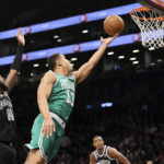 Boston Celtics guard Malcolm Brogdon (13) drives to the basket against Brooklyn Nets forward Royce O'Neale (00) as Nets forwards Joe Harris, right, and forward Nic Claxton, second from right, watch during the first half of an NBA basketball game, Sunday, Dec. 4, 2022, in New York. (AP Photo/Jessie Alcheh)