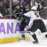 Arizona Coyotes' Troy Stecher, right, checks Vancouver Canucks' Conor Garland during the first period of an NHL hockey game in Vancouver, British Columbia on Saturday, Dec. 3, 2022. (Darryl Dyck/The Canadian Press via AP)