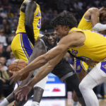 Sacramento Kings center Neemias Queta and Los Angeles Lakers guard Max Christie, right, scramble for the ball during the first half of an NBA basketball game in Sacramento, Calif., Wednesday, Dec. 21, 2022. (AP Photo/José Luis Villegas)