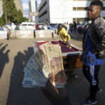 
              A person holds banknotes as people play pool in an open space in Harare, Zimbabwe, Wednesday, Nov. 30, 2022. Previously a minority and elite sport in Zimbabwe, the game has increased in popularity over the years, first as a pastime and now as a survival mode for many in a country where employment is hard to come by. (AP Photo/Tsvangirayi Mukwazhi)
            