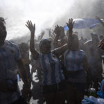 
              Soccer fans waiting for a homecoming parade for the players who won the World Cup title, are cooled off with water sprayed by municipal workers, in Buenos Aires, Argentina, Tuesday, Dec. 20, 2022. A parade to celebrate the Argentine World Cup champions was abruptly cut short Tuesday as millions of people poured onto thoroughfares, highways and overpasses in a chaotic attempt to catch a glimpse of the national team. (AP Photo/Rodrigo Abd)
            