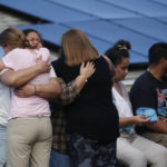 
              People embrace on a street in Kailua, where at least a man died and a few others were seriously injured while building a retaining wall in Honolulu on Friday, Dec. 30, 2022. (Cindy Ellen Russell/Honolulu Star-Advertiser via AP)
            