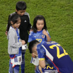 Japan's Maya Yoshida kneels in front of children after the World Cup round of 16 soccer match between Japan and Croatia at the Al Janoub Stadium in Al Wakrah, Qatar, Monday, Dec. 5, 2022. (AP Photo/Luca Bruno)