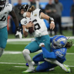 Jacksonville Jaguars quarterback Trevor Lawrence (16) is sacked by Detroit Lions linebacker James Houston (59) during the first half of an NFL football game, Sunday, Dec. 4, 2022, in Detroit. (AP Photo/Paul Sancya)