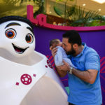 
              Nizar Chalghen, of Syria, kisses his 1-month-old son, Aram, while posing in front of La'eeb, the official mascot of the FIFA World Cup soccer tournament during a trip to Mall of Qatar in Al Rayyan, Qatar, Sunday, Dec. 4, 2022. (AP Photo/Julio Cortez)
            