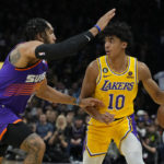 Los Angeles Lakers guard Max Christie (10) shields the ball from Phoenix Suns forward Ish Wainright during the first half of an NBA basketball game, Monday, Dec. 19, 2022, in Phoenix. (AP Photo/Rick Scuteri)