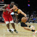 Phoenix Suns guard Devin Booker, right, drives past New Orleans Pelicans forward Zion Williamson during the second half of an NBA basketball game, Saturday, Dec. 17, 2022, in Phoenix. The Suns defeated the Pelicans 118-114. (AP Photo/Matt York)