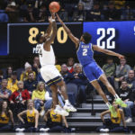 West Virginia guard Seth Wilson (14) shoots while defended by Buffalo guard Kidtrell Blocker (2) during the first half of an NCAA college basketball game in Morgantown, W.Va., Sunday, Dec. 18, 2022. (AP Photo/Kathleen Batten)