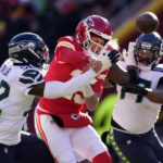 Kansas City Chiefs quarterback Patrick Mahomes is hit as he throws by Seattle Seahawks defensive end Darrell Taylor (52) during the first half of an NFL football game Saturday, Dec. 24, 2022, in Kansas City, Mo. (AP Photo/Charlie Riedel)